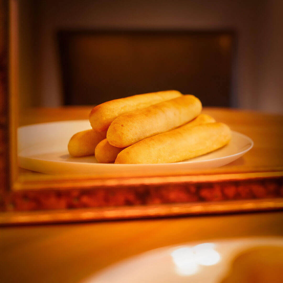 A small stack of beautiful breadsticks on a plate is reflected in a mirror 
