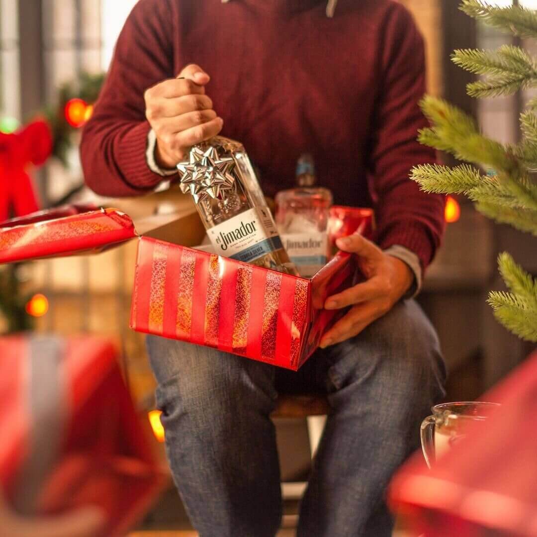 Man opens up Christmas present and finds tequila with silver bow 