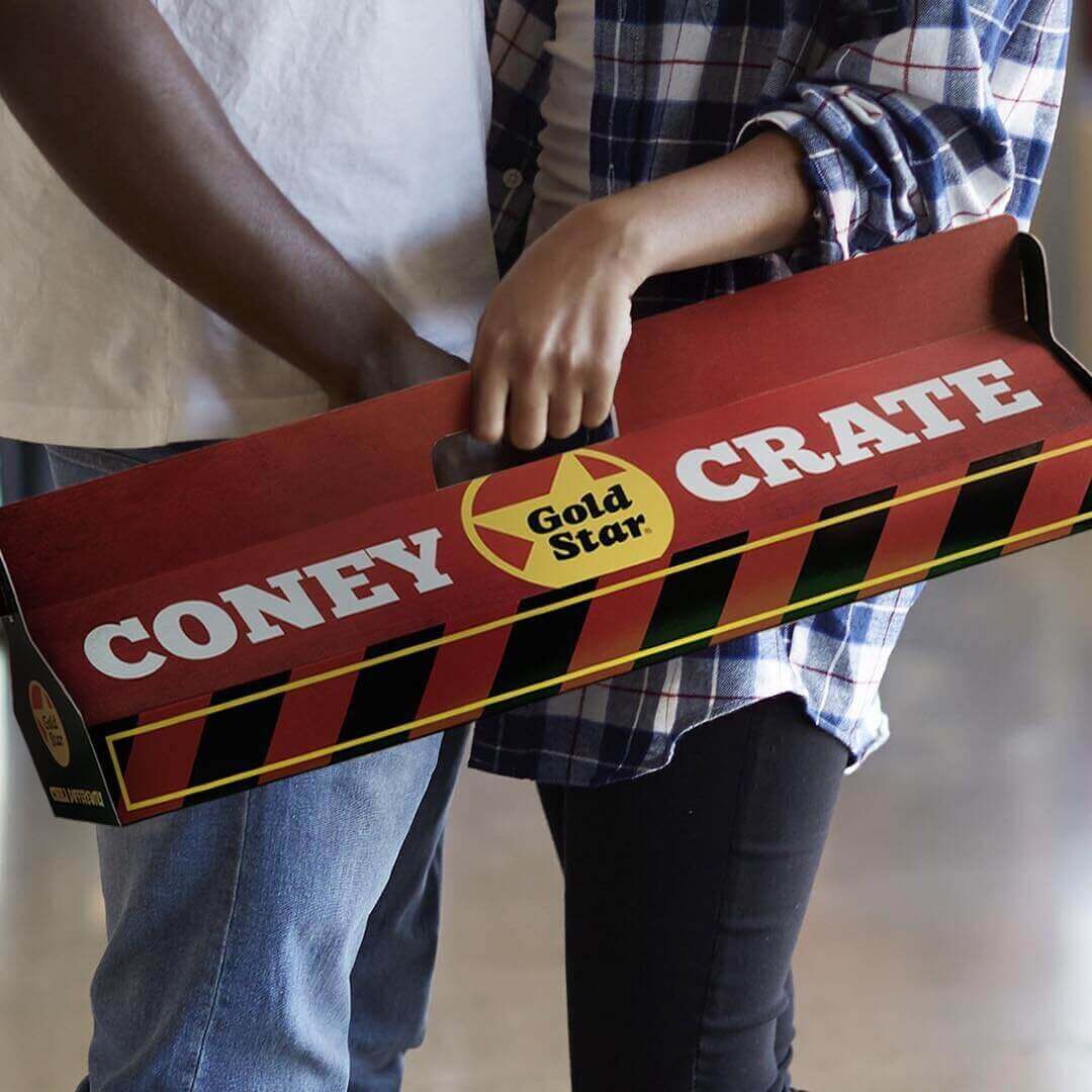Photo of young couple carrying to-go crate filled with Cincinnati-style chili cheese coneys  